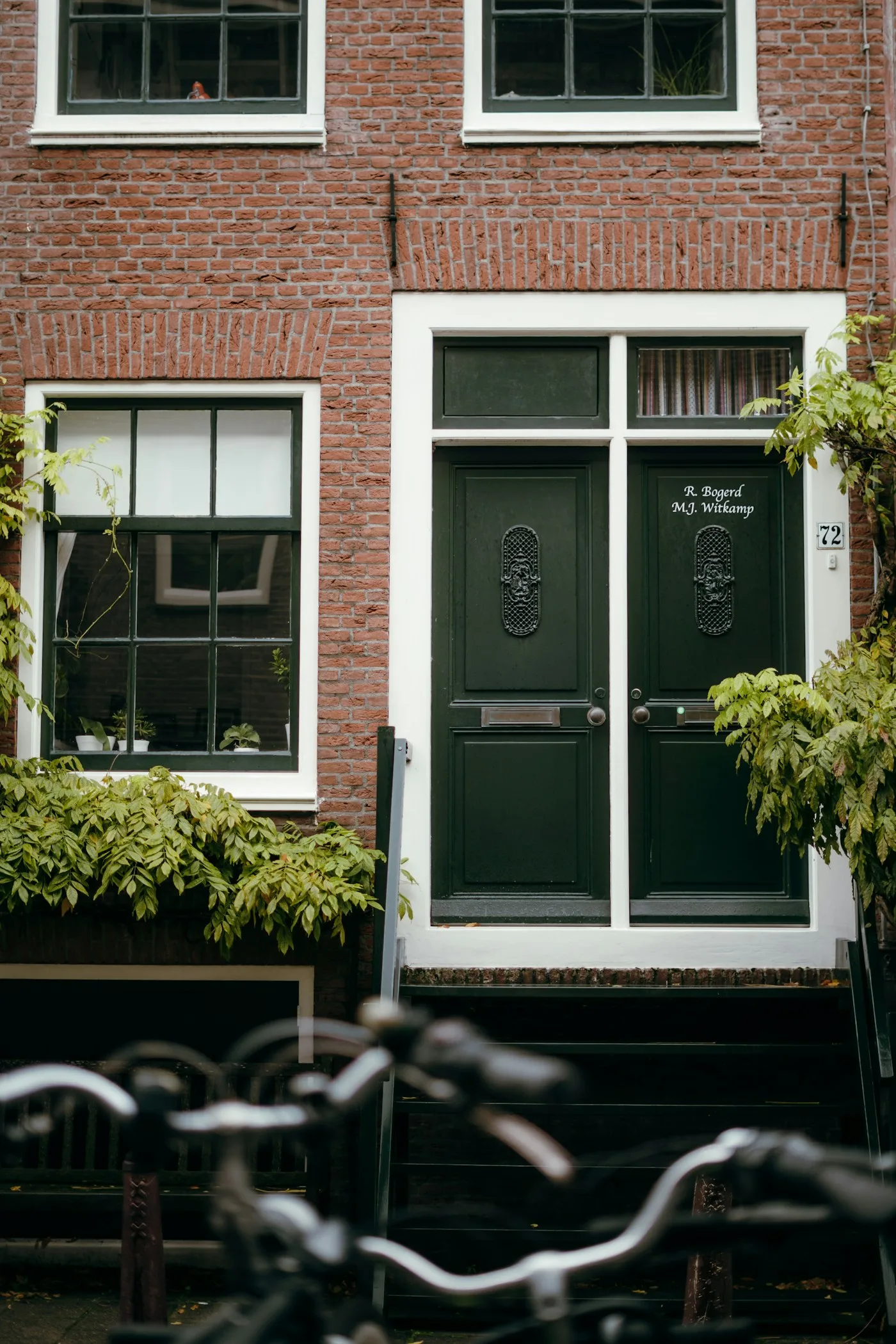 Voorbeeld van een bakstenen gevel met donkergroene houten deuren
