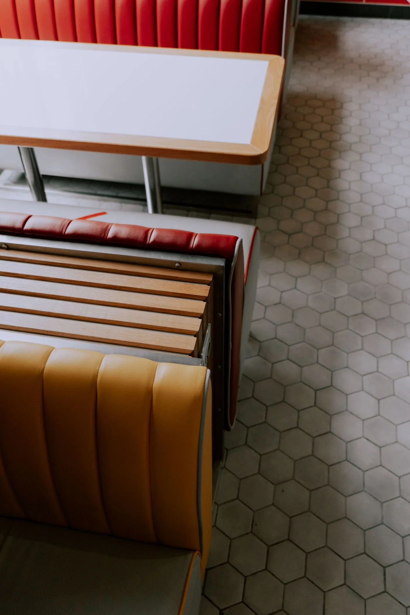 Een eettafel tussen rode en gele zitbanken in een snackbarachtige eetzaak