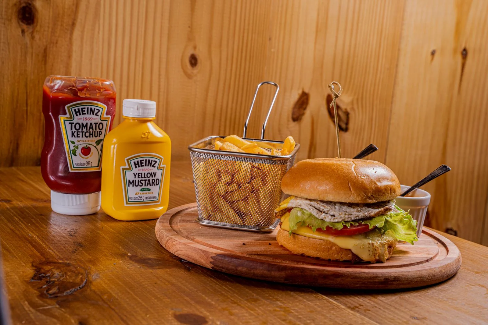 Echte foto van een burger met kaas en een mandje friet op een houten plateau