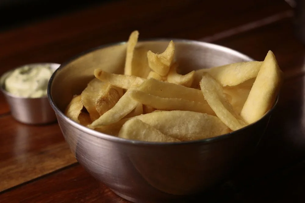Goudgele friet in een metalen kom met saus ernaast